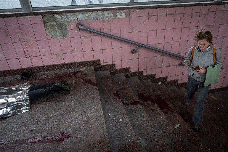 A woman walks next to the body of a man killed during shelling in Kharkiv, eastern Ukraine.