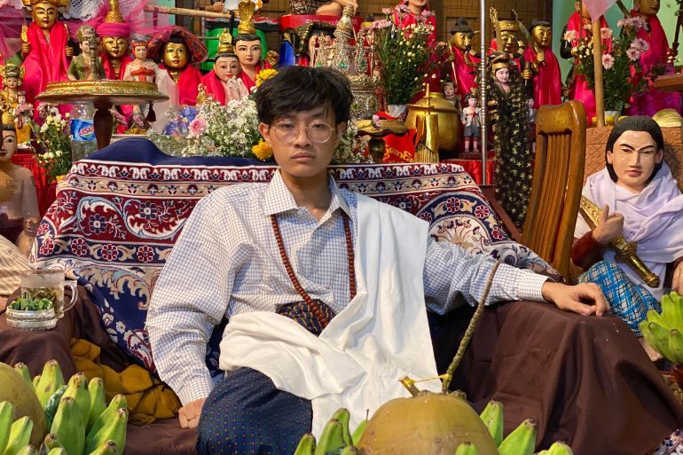A wizard sits in an elaborately decorated room in Myanmar