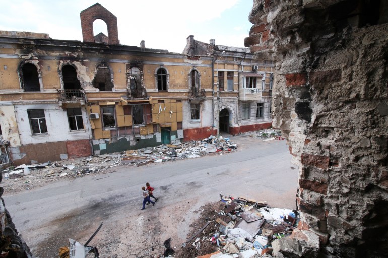 Children walk among buildings destroyed during fighting in Mariupol, eastern Ukraine, Wednesday, May 25, 2022