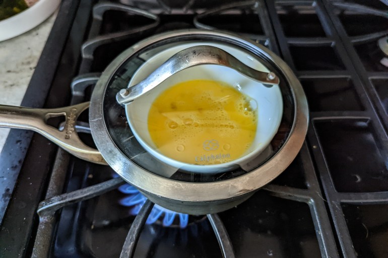 A view of a pan steamer on a gas flame with a bowl of beaten eggs in it, about to be steamed