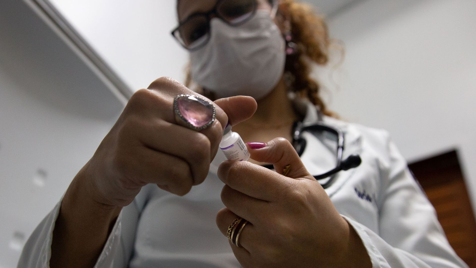 Pediatrician Carla Carvalho reads the side of a vial of measles vaccine