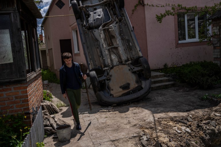 A resident carries a shovel to clear the rubble from his house damaged during a shelling in Kharkiv