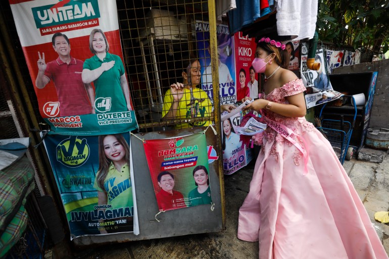 A Robredo supporter dressed in a long pink ball gown for the 'Flowers of May' goes door to door in a Quezon City neighbourhood