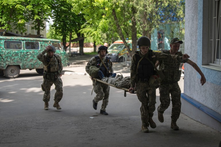 Ukrainian servicemen carry an injured comrade on stretcher to the hospital after an attack by Russian forces in Donetsk region, Ukraine