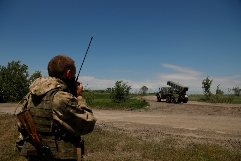 A Donetsk People's Republic militia serviceman speak on a communication device prior to fire with a multiple rocket launcher from its position not far from Panteleimonivka, in Russian-occupied territory, eastern Ukraine, Saturday, May 28, 2022