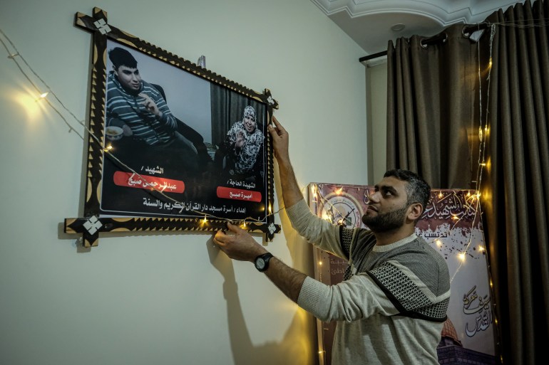 A man hangs a photo of his deceased mother and brother