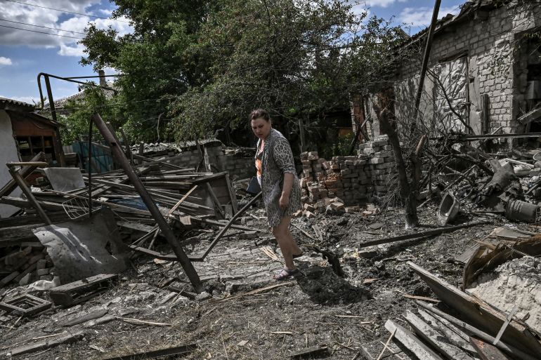 A woman stands at the yard of her destroyed house in the city of Lysychansk at the eastern Ukrainian region of Donbas on June 7, 2022. (Photo by ARIS MESSINIS / AFP)