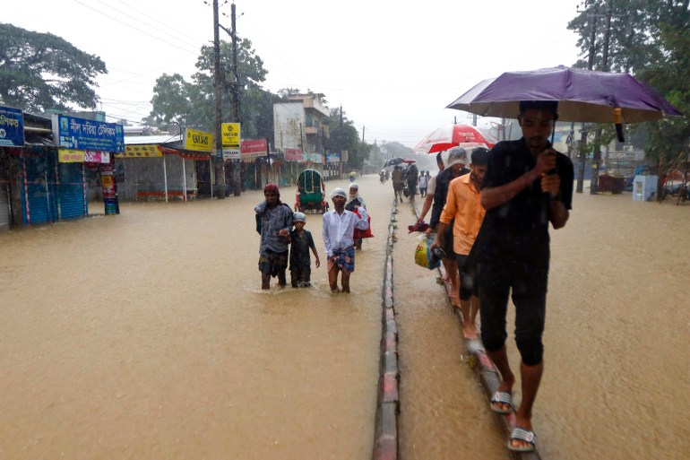 People wade along a road in a flooded area 