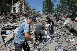 Employees of the Liubotinsky Lyceum of Railway Transport and local residents dismantle the ruins of an administrative building, as result of the explosion of a Russian rocket, in Lyubotyn, Kharkiv region, on June 20, 2022. (Photo by SERGEY BOBOK / AFP)