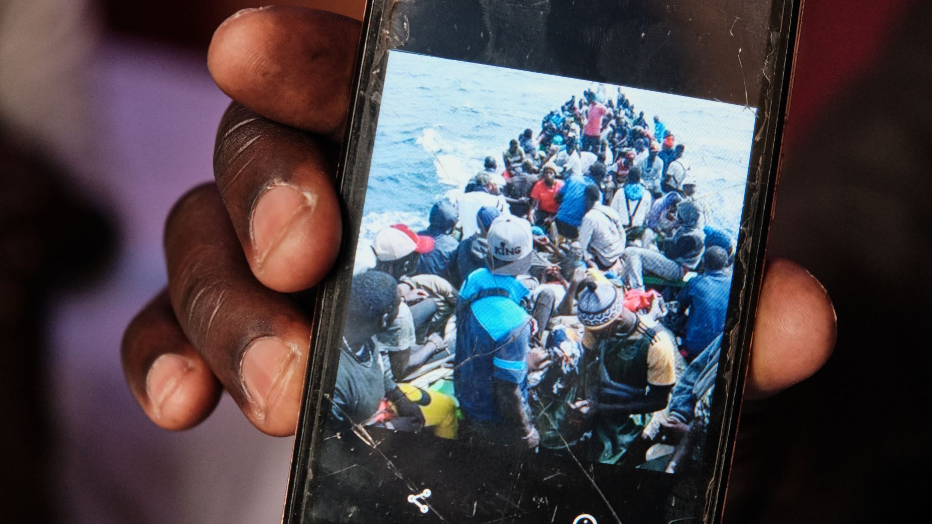 A photo of a person showing a cellphone photo taken during his six-day crossing to the Canary Islands with a small boat filled with people.