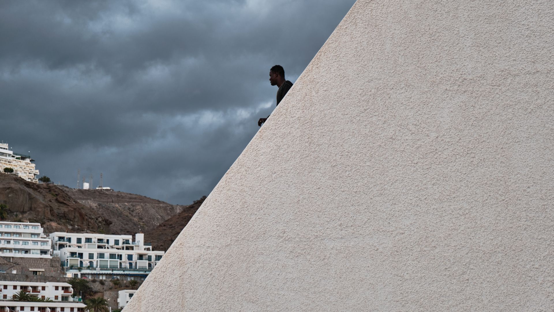 A photo of a young man from Senegal looking out at the horizon from the top of a building.