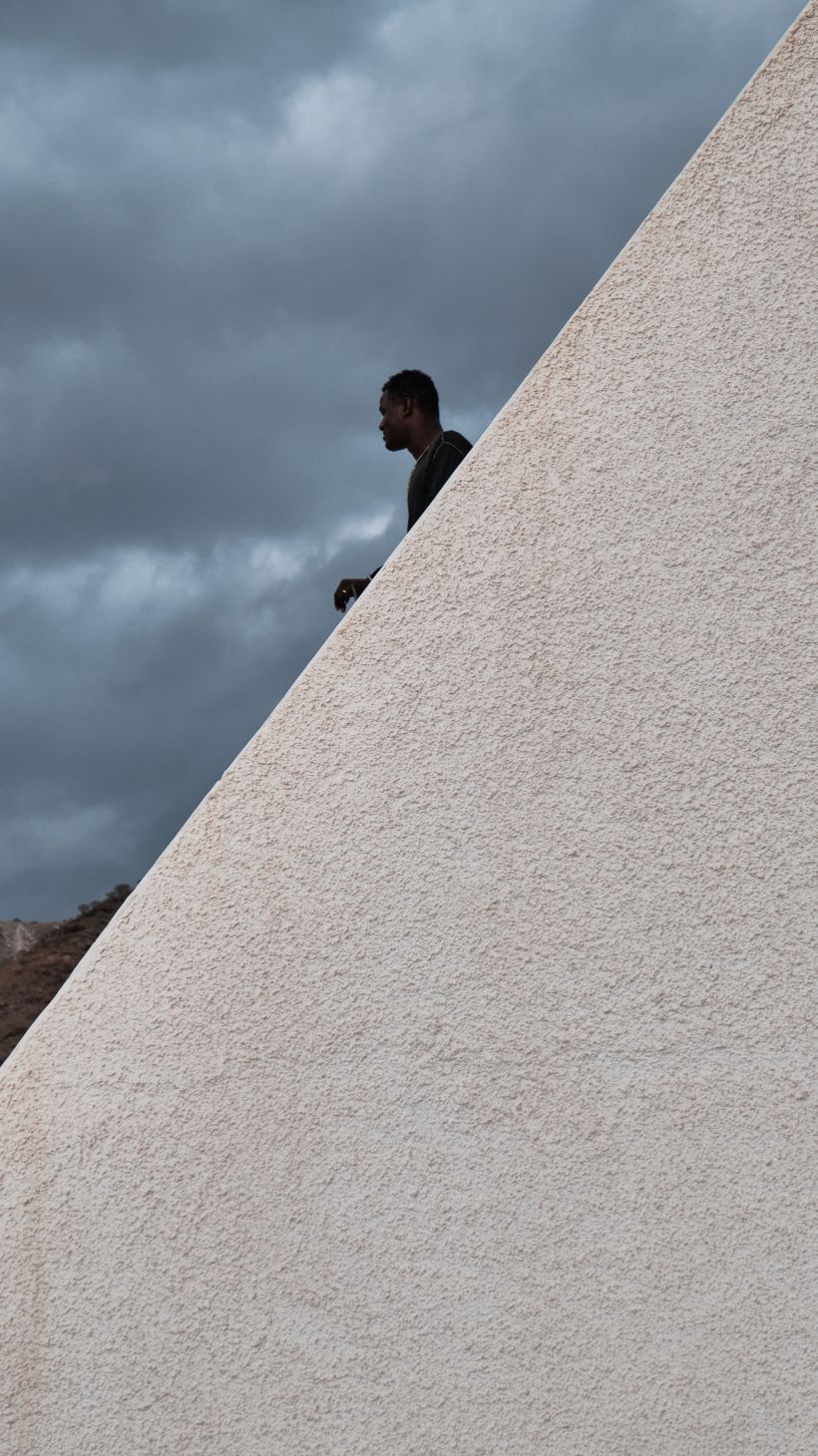 A photo of a young man from Senegal looking out at the horizon from the top of a building.