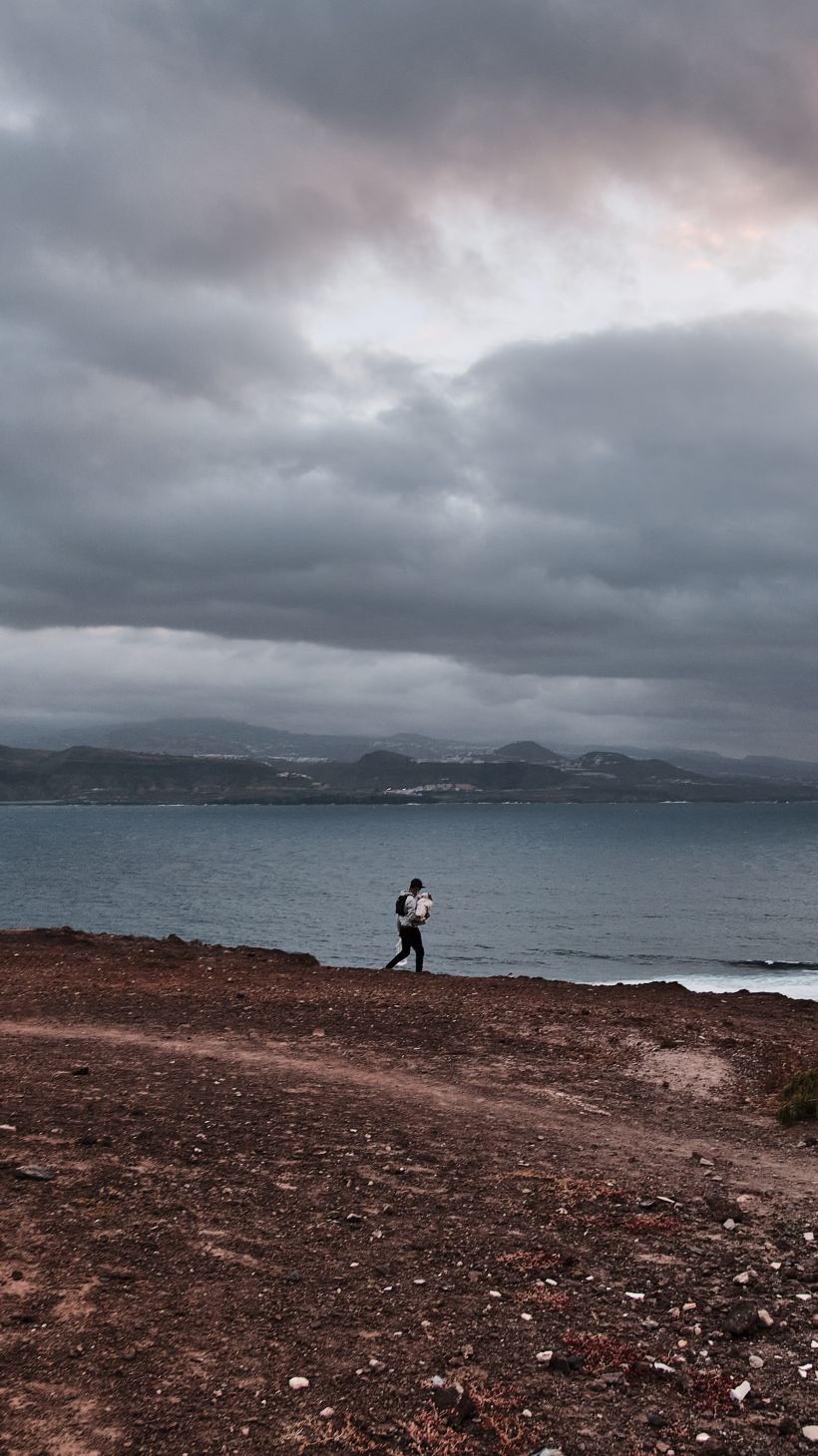 A photo of a man from Morocco carries food supplies to his tent settlement by the sea.