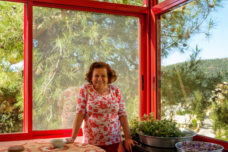 Salma standing in her light, airy kitchen with pine trees visible out of the window behind her