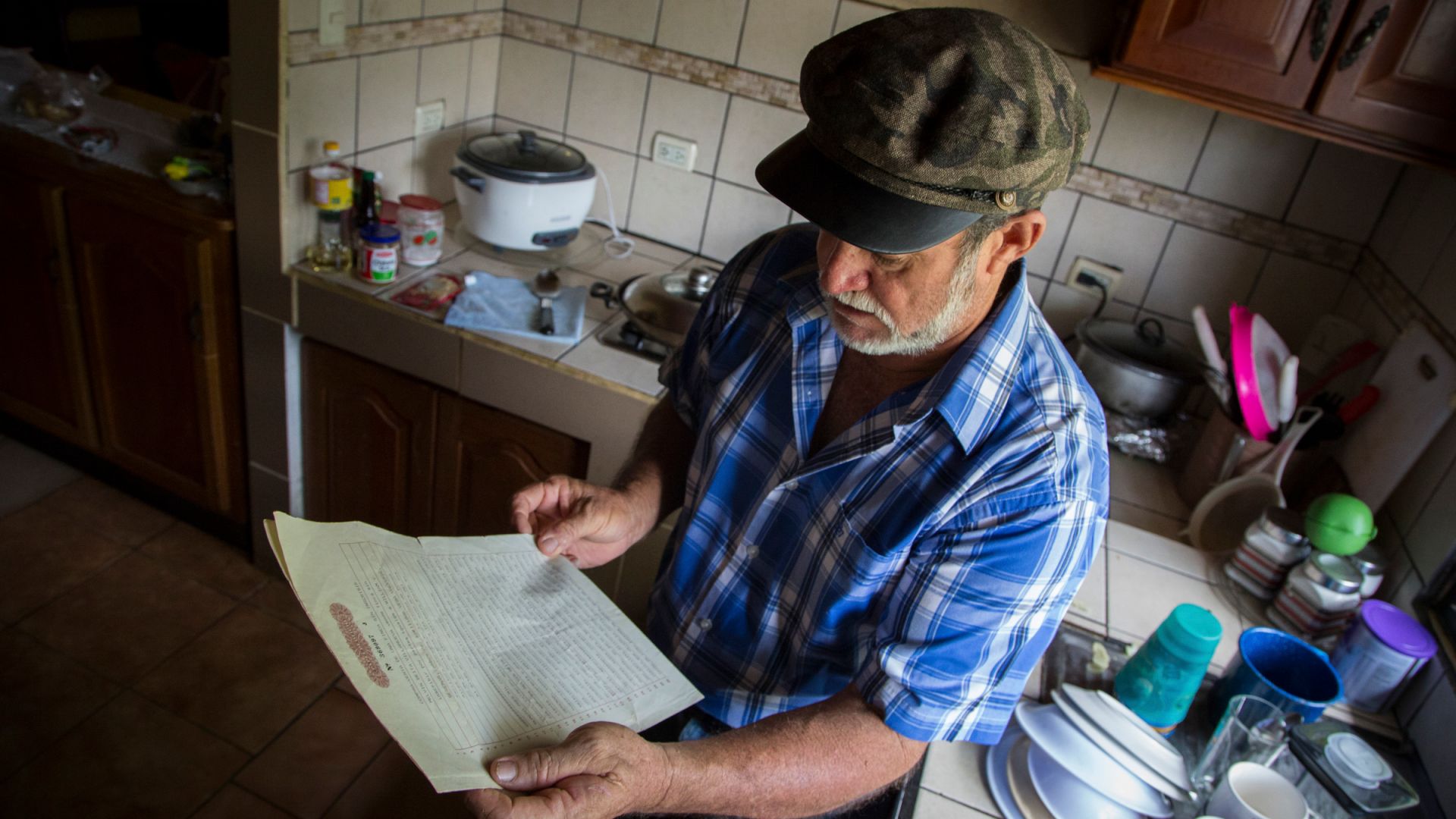 A photo of William Vega, 60, in his kitchen, holding the deed to the 100-hectare (247-acre) farm.