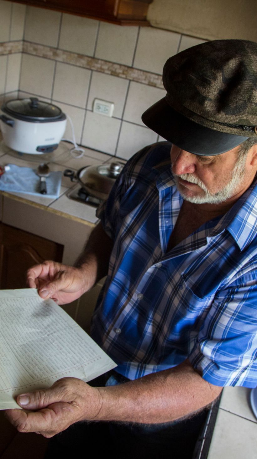 A photo of William Vega, 60, in his kitchen, holding the deed to the 100-hectare (247-acre) farm.