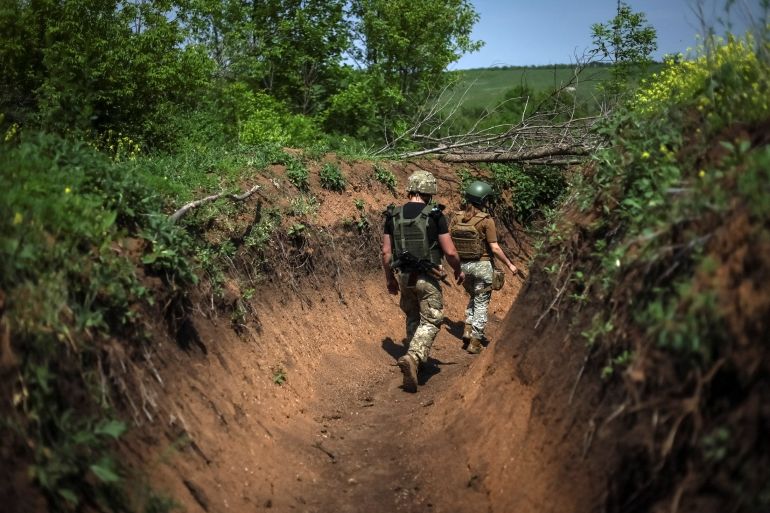 Ukrainian troops are seen walking through a trench in eastern Ukraine's Donbas region