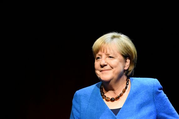 Angela Merkel in bright blue jacket with a bead necklace.