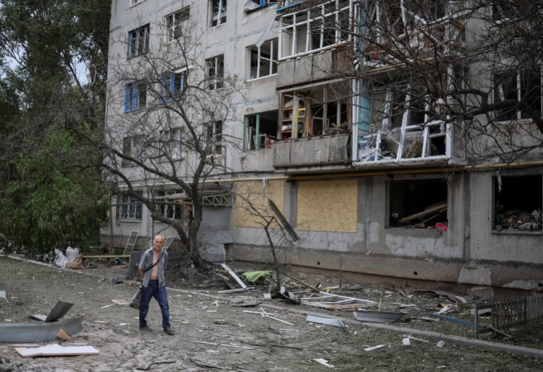 A resident walks by a damaged apartment building in Ukraine