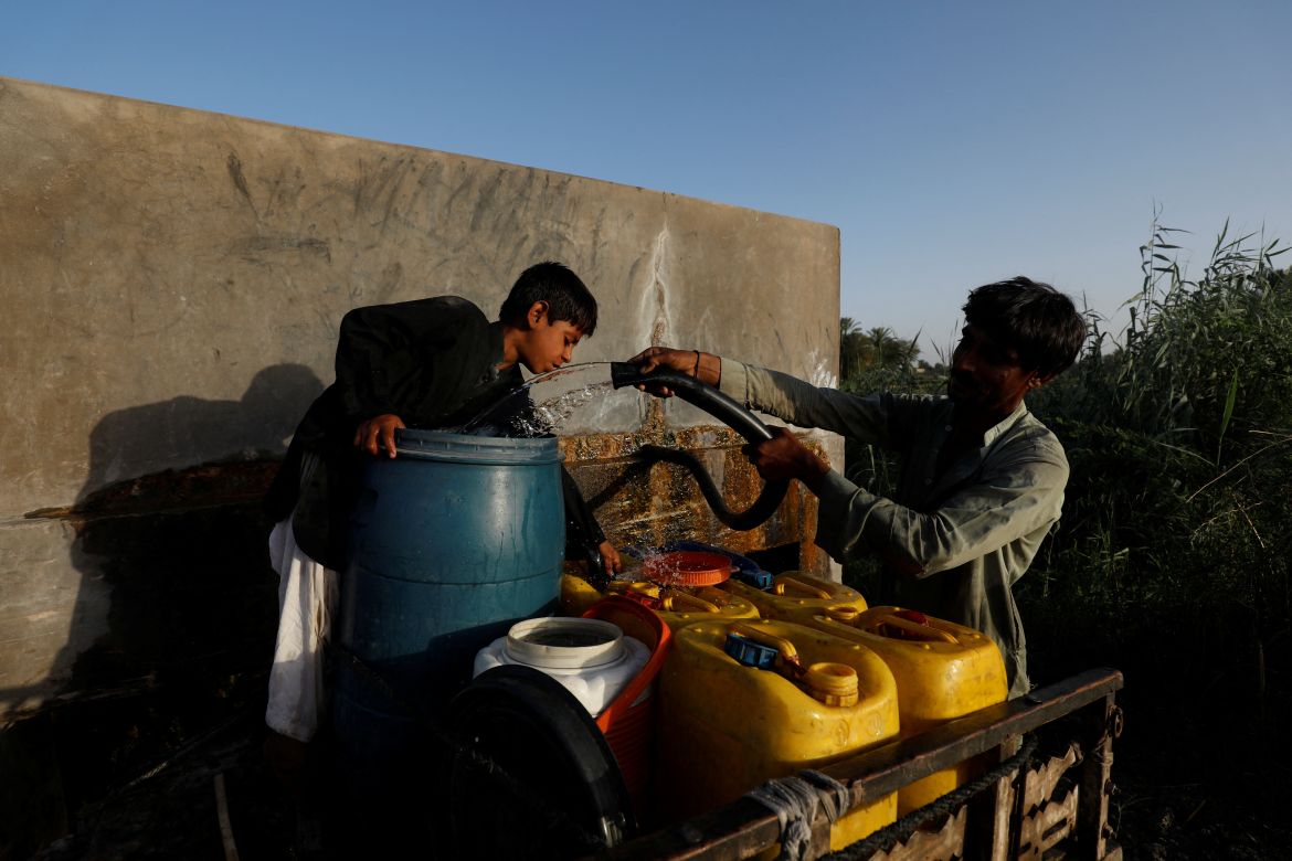 A father and his son fill water canisters from a private pump to sell door-to-door,