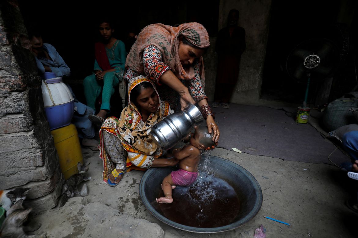 Rehmat, 30, helps Razia, 25, bathe her six-month-old daughter Tamanna to cool off during a heatwave
