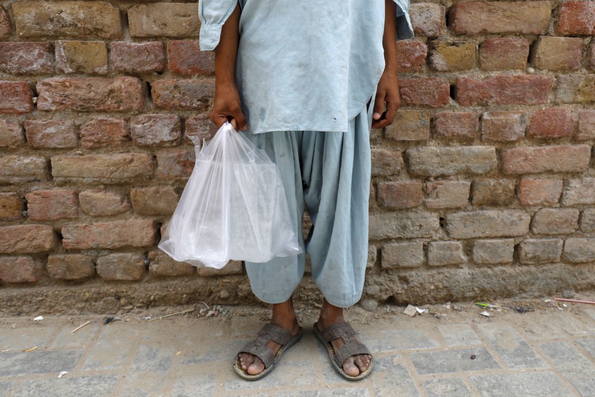 Siraj, 8, carries bags of ice purchased for his family from a nearby stall, in a residential area in Jacobabad