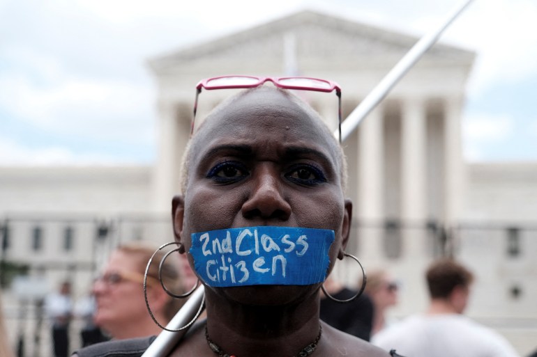 An abortion rights demonstrator tapes her mouth outside the United States Supreme Court as the court rules in the Dobbs v Women's Health Organization abortion case, overturning the landmark Roe v Wade abortion decision in Washington, U.S., June 24, 2022.