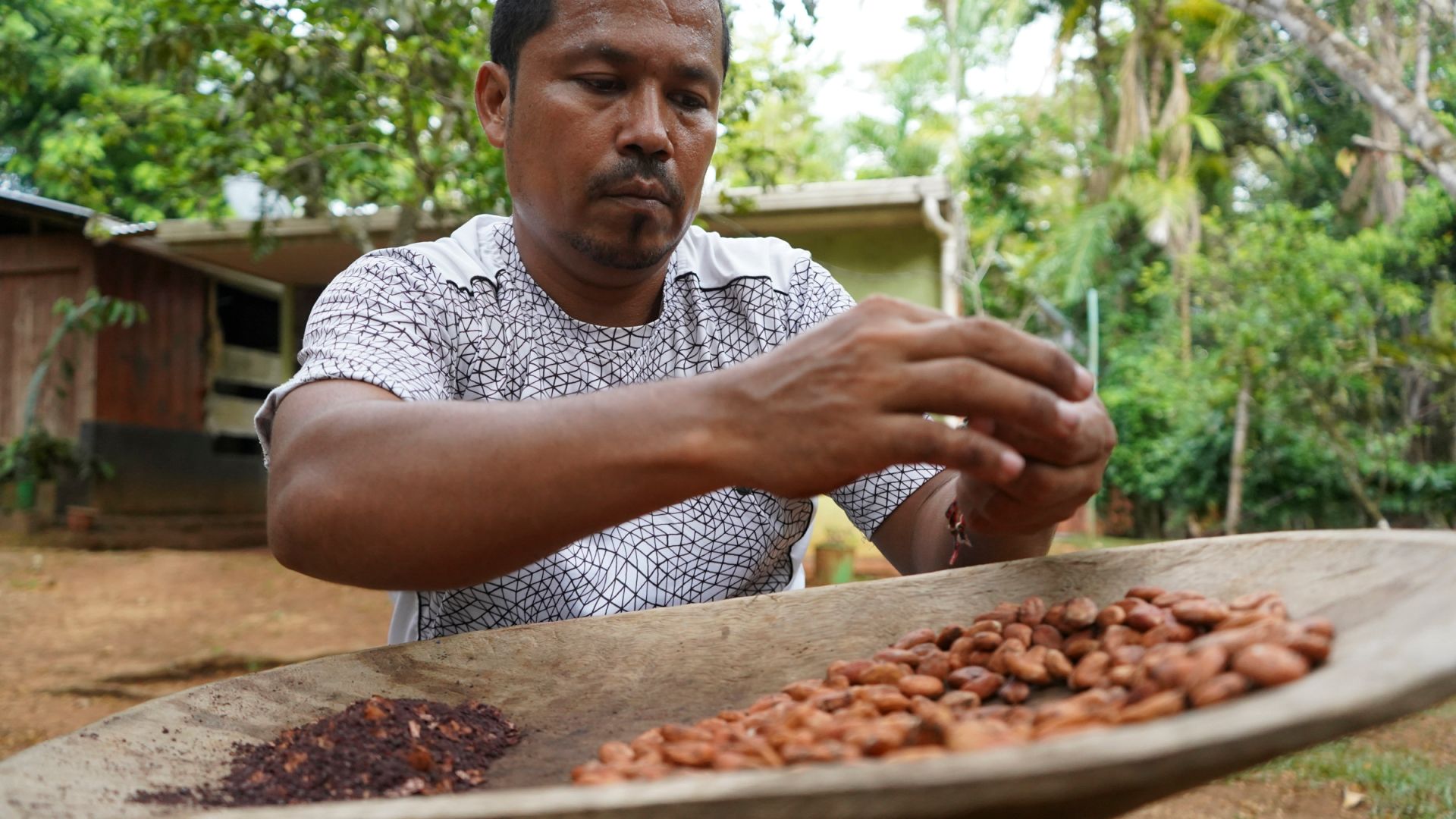 A photo of Jeffrey Villanueva, 44, crushing cocoa beans at his family home.
