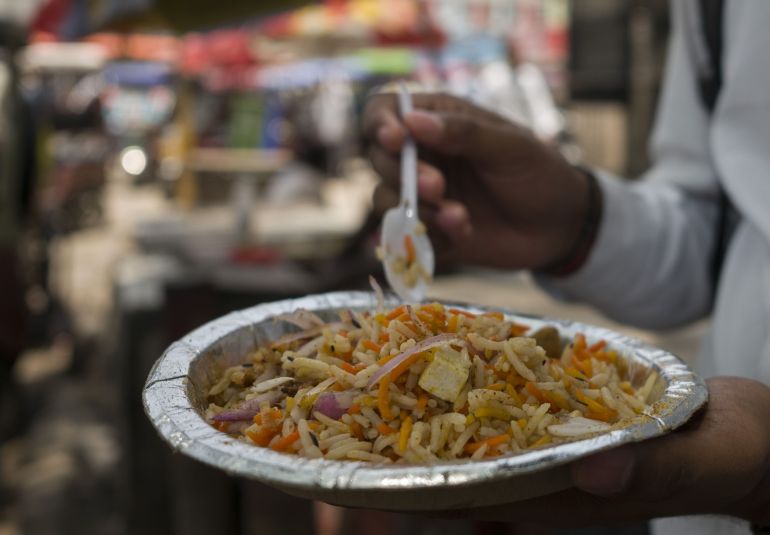 A customer eats a portion of rice 'Biryani' at a roadside food stall in New Delhi, India