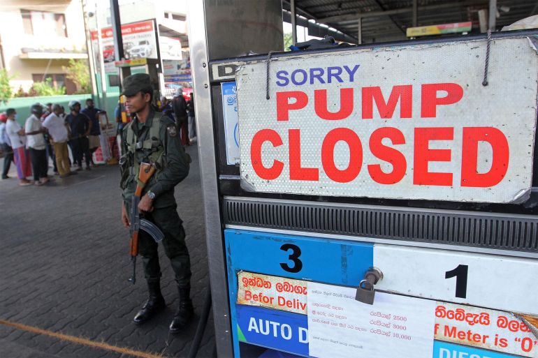 A member of Sri Lankan security personnel stands guard outside a fuel station that ran out of gasoline in Colombo, Sri Lanka