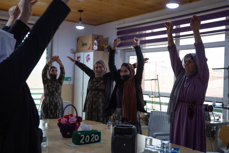 A photo of women standing around a table with their hands up in the air.