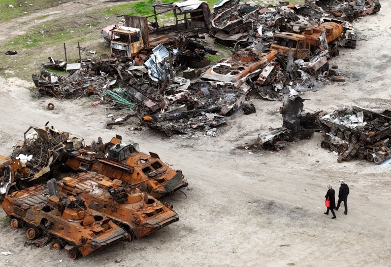 People walk past wrecks of military vehicles in Bucha, on the outskirts of Kyiv, Ukraine, April 30, 2022.