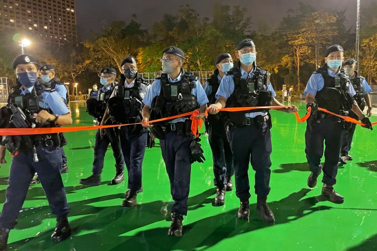 Hong Kong police walk with a red tape across Victoria Park to ensure no-one holds a vigil to remember the Tiananmen Square massacre