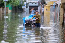 A man pushes his cart through floodwaters
