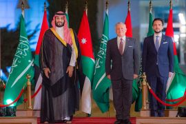 Saudi Crown Prince Mohammed bin Salman, King Abdullah II of Jordan and his son, Crown Prince Hussein bin Abdullah stand together for a photo in front of Saudi and Jordanian flags.