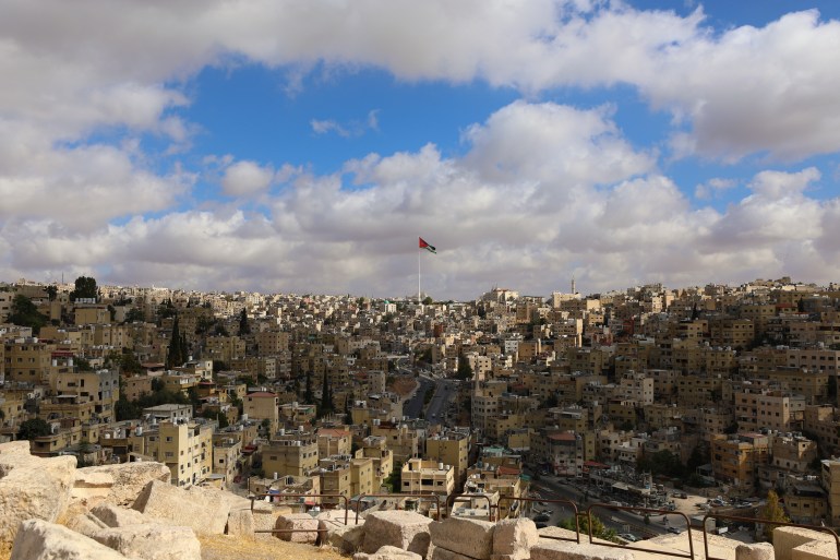 The sun illuminates part of the city and the national flag of Jordan
