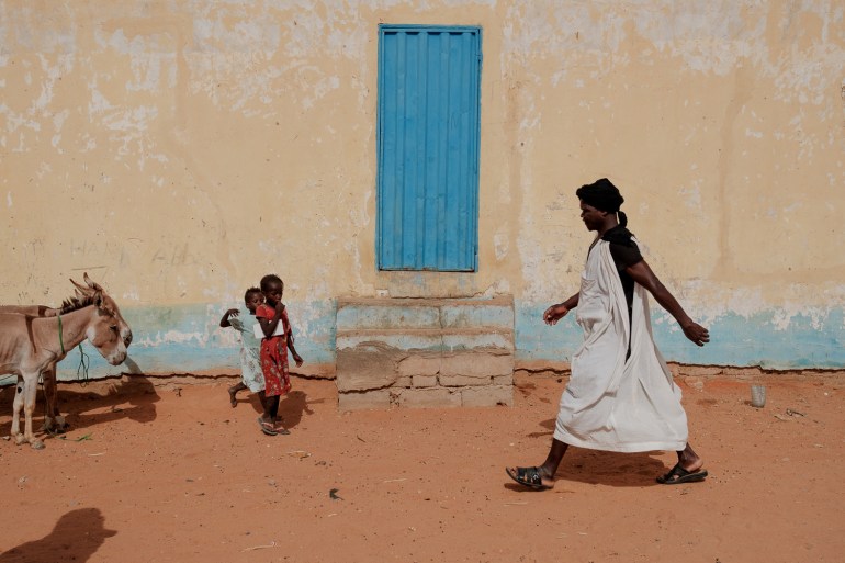 Malian refugees walk past a building on their way to the Mbera camp weekly marke