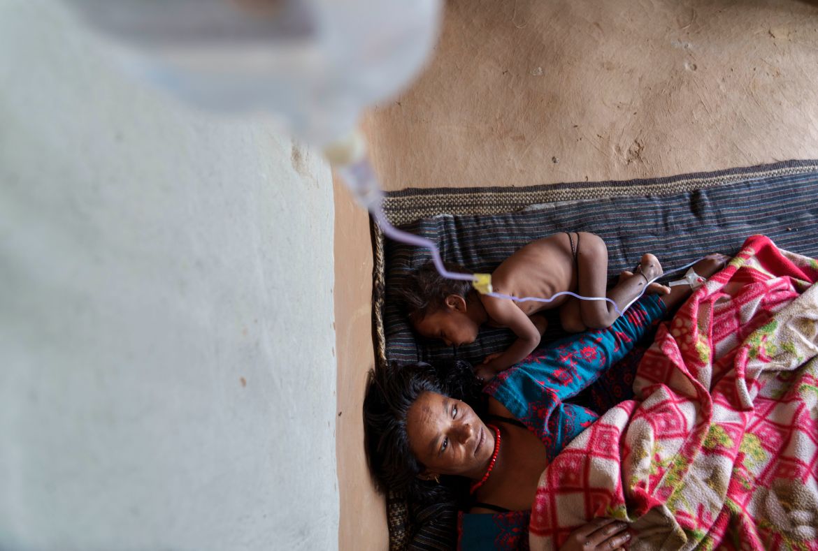 Nirmala Bishwokarma, 25 with her malnourished baby lie down at her home in Muktikot