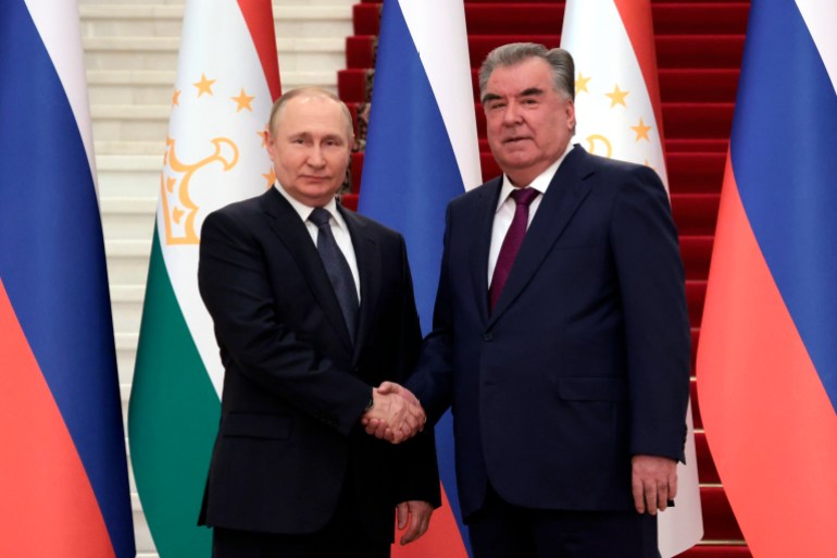 Russian President Vladimir Putin and Tajikistan's President Emomali Rahmon shake hands will posing for a photo.