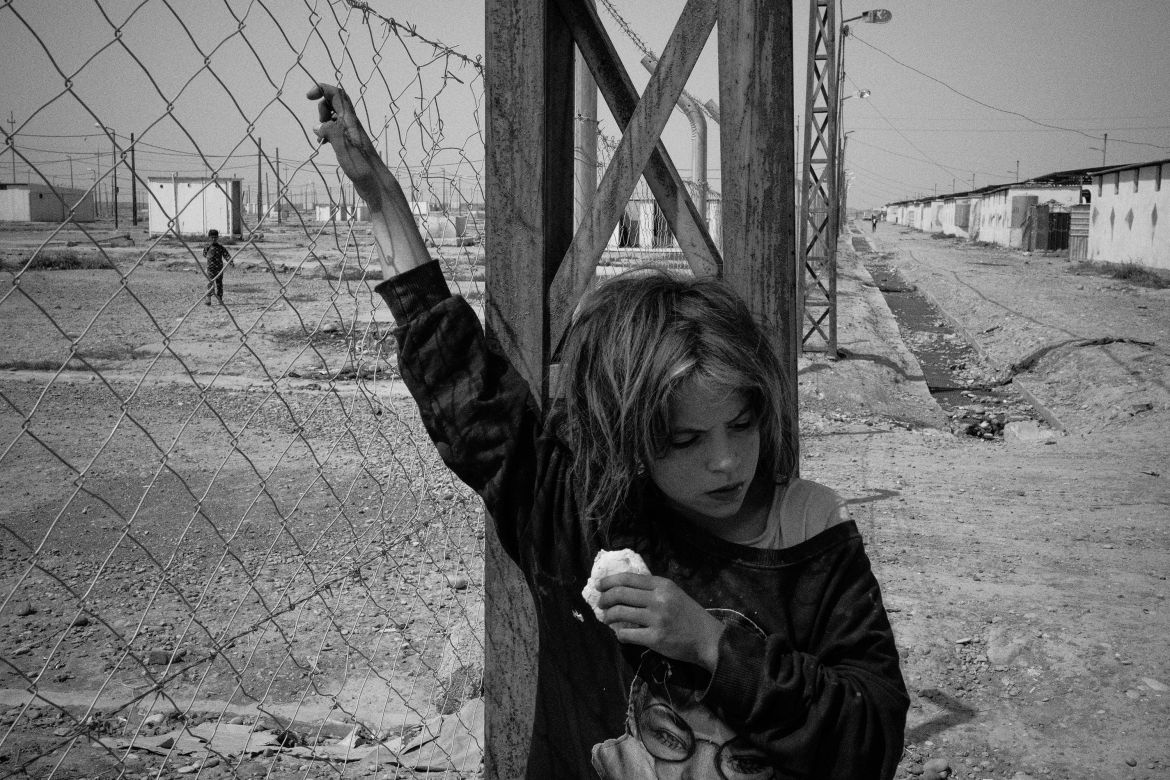Iraq, Jeddah 5 camp. A young girl leans on the separation fence between different sections of the camp.