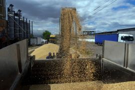A photo of a worker loading a truck with grain.