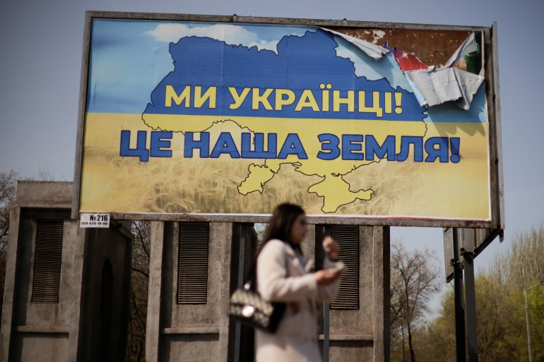 A Ukrainian woman passes in front of a billboard reading "We str Ukrainians, this is our land", in the town of Kryvyi Rih, Dnipropetrovsk region, Ukraine April 25, 2022 