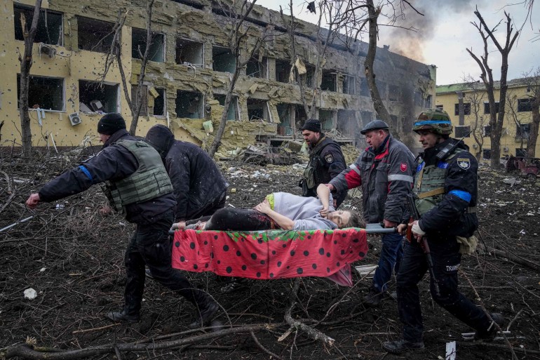 Ukrainian emergency employees and volunteers carry an injured pregnant woman from a maternity hospital that was damaged by shelling in Mariupol, Ukraine, March 9, 2022.