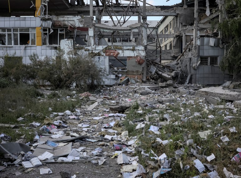 Textbooks lie scattered across the ground near a destroyed school after a morning shelling
