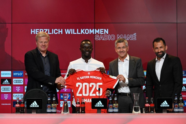 Bayern Munich's Senegalese new forward Sadio Mane (2L) with his jersey poses next to Bayern Munich CEO Oliver Kahn (L), President Herbert Hainer (2ndR) and Sporting Director Hasan Salihamidzic during a press conference after he signed a three-year deal with German first division football club FC Bayern Munich, in Munich, southern Germany