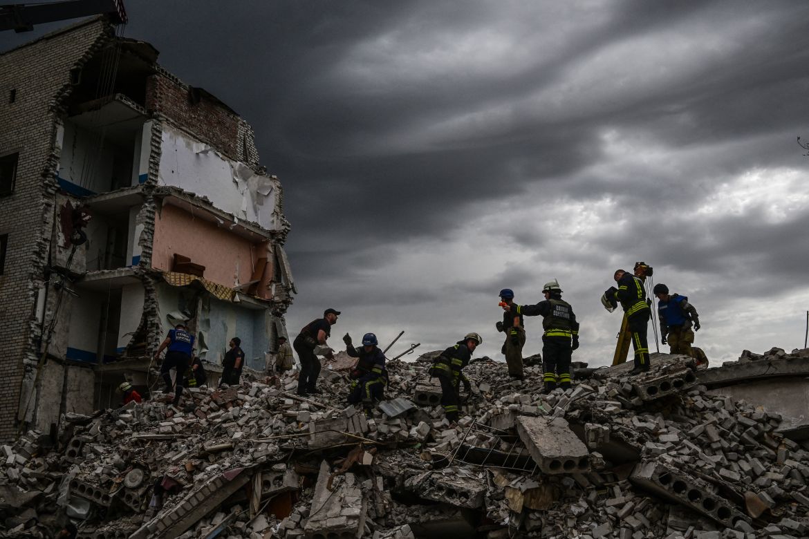 Firefighters and members of a rescue team clear the scene after a building was partialy destroyed following shelling, in Chasiv Yar