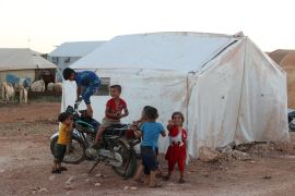 Children play by a motorcycle outside a tent at the "Blue camp" for Syrians displaced by conflict near the town of Maaret Misrin in the rebel-held northern part of the northwestern Idlib province during the Muslim holiday of Eid al-Adha on July 10, 2022.