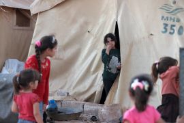 A young girl looks out from her tent to two other girls at a camp near Maaret for Syrians forced from their homes by conflict.