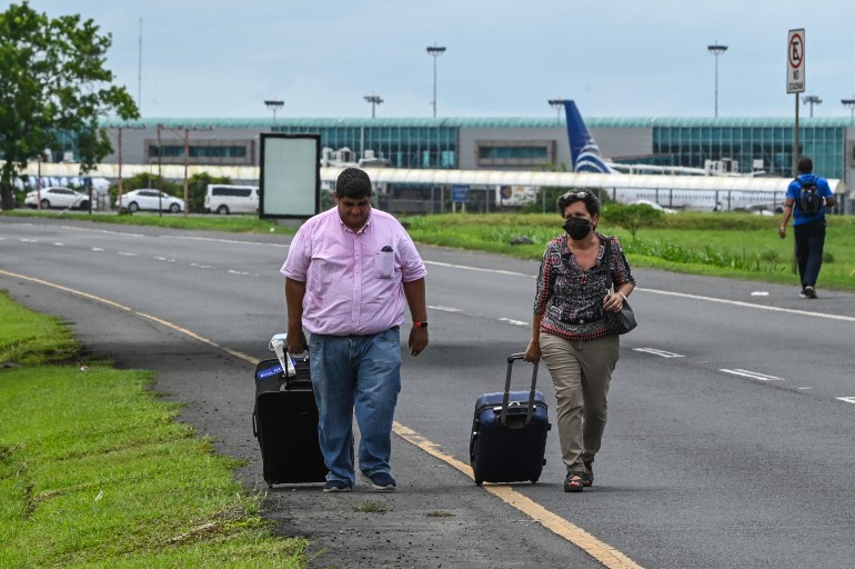 Passengers walk as union workers block the entrance to the Tocumen International airport, in Panama City, on July 18, 2022. - Panama's government and indigenous leaders reached a second deal Sunday to clear all remaining demonstrators from the Panamerican Highway in exchange for lower fuel prices, ending a two-week blockade that had stymied food deliveries. (Photo by Luis ACOSTA / AFP)