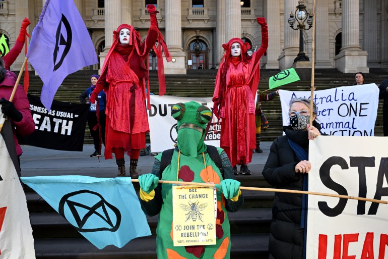 Campaigners, one dressed as a turtle and some in red robes, demand action on climate change as the government releases the State of the Environment report